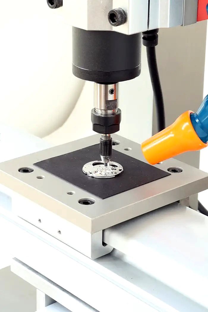 Machine à perler ERI réalisant un perlage sur une platine de montre